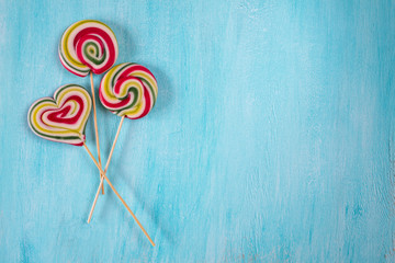 Cute colorful round lolipop and lollipop looks like a heart on turquoise copy space background