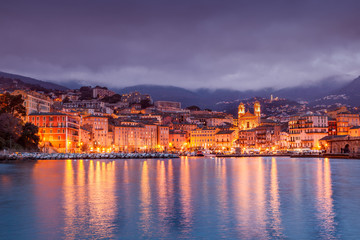 Bastia, a beautiful city landscape, a port with boats, a sunset and the lights of a night city. France, Corsica, a popular destination for travel in Europe - obrazy, fototapety, plakaty