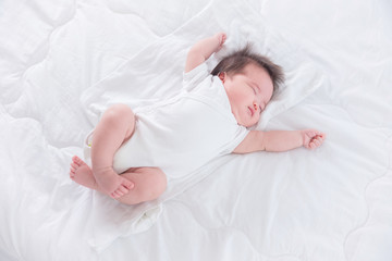 Little asian infant sleeping on white bed in the morning