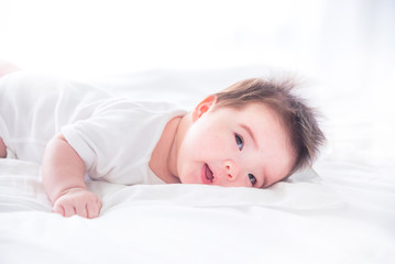 Little asian infant waking up on white bed in the morning