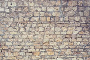 Part of a uneven stone wall with cement Background, texture