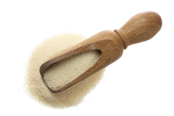 raw semolina in wooden scoop isolated on white background. Top view