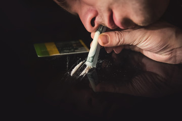 Young addict snorting white cocaine through