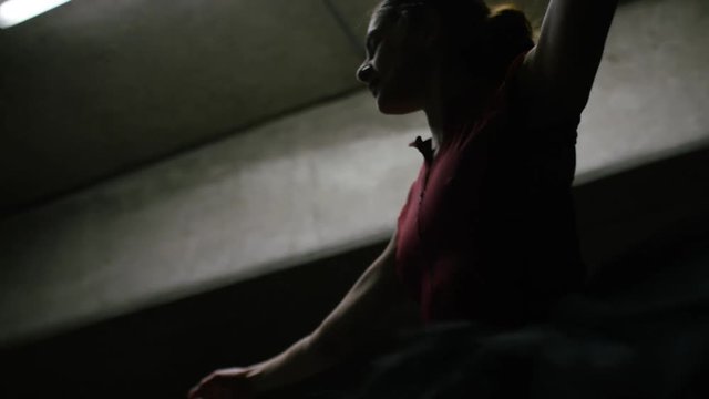 Handheld shot of ballet dancer dancing in a car park, shot from the waist up