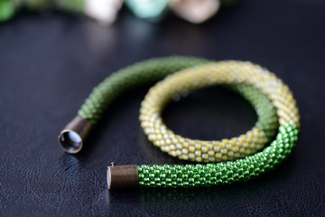 Bead crochet necklace three shades of green on a dark background close up