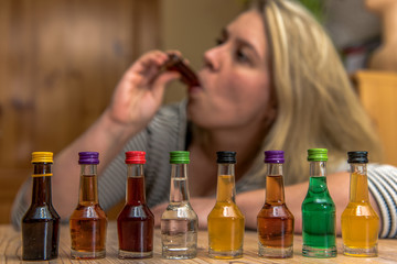 A woman (25-30) drinks from a small bottle of alcohol. Concept: alcohol abuse or drinking