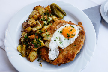 tasty german Schnitzel with fried egg and potatoes