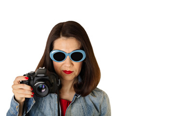 Woman in denim shirt and blue sunglasses holding a camera.