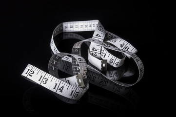 white measuring tape on black with reflection