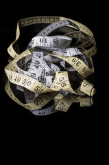 White and yellow measuring tape on black with reflection