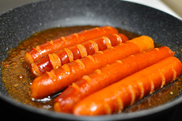 Sausage frying in oil in a small pan. Fresh sausage for breakfast