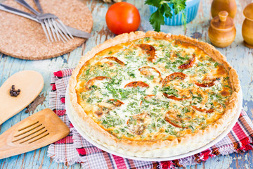 Homemade french quiche pie with tomato, cheese and herb on a plate