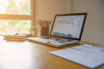 Laptop with financial documents on wooden table