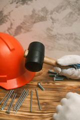 Rubber hammer, tools and construction helmet on wooden board background, top view, closeup