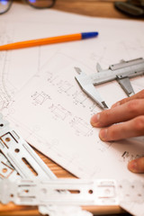Construction plans, pen and measure tools on wooden board background, top view, closeup