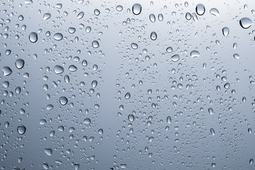 Rain drops on a glass. Blue background.
