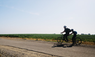 Obraz na płótnie Canvas father and son ride a tandem bike