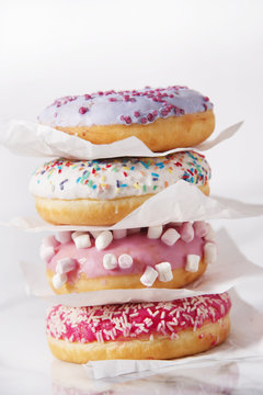 Pile of donuts on marble pattern tabletop. Sweetness and happiness concept.