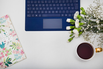 Cup of tea, computer, notebook and flowers
