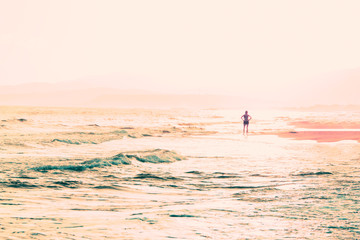 Fototapeta na wymiar Woman on the beach at sunrise