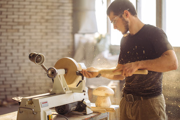 carpenter man working at small wood lathe, an artisan carves piece of wood using manual lathe