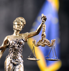 Scales of Justice, Justitia, Lady Justice in front of the European Union flag in the background.