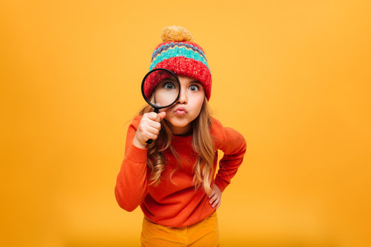 Naklejki Joyful Young girl in sweater and hat looking at camera
