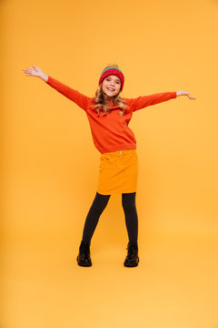 Full length image of Playful girl in sweater and hat