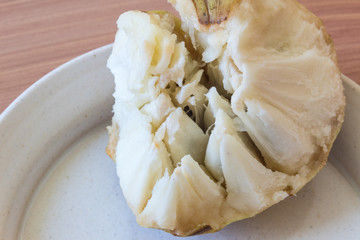 Piece of ripe cherimoya fruit Annona cherimola broken apart to reveal inner texture, centered, horizontal aspect