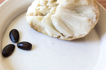 Shallow dish with black seeds and fruit of cherimoya Annona cherimola, copy space, horizontal aspect