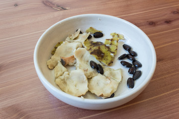 Small dish with pieces of skin and seeds from an eaten cherimoya fruit, Annona cherimola, on wood background, horizontal aspect