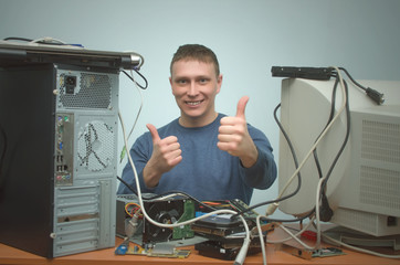 Happy smiling repairman is repairing the computer and is showing a thumbs up. Computer technician. PC repair service center.