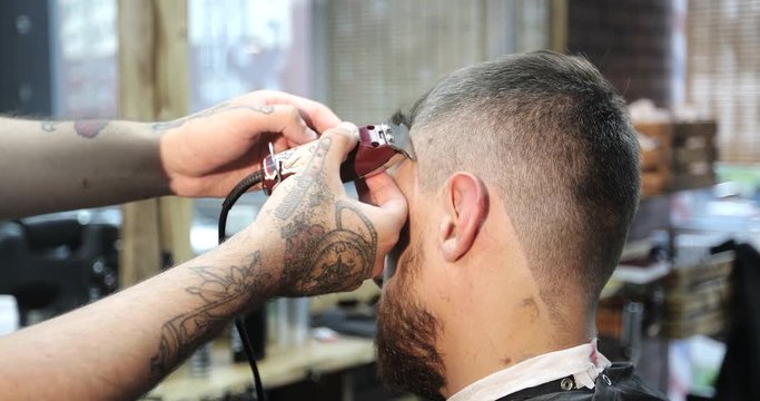 A hairdresser with tattoos on his hands makes a beautiful pattern