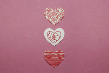 Three white and red heart-shaped decorations on pink background. Valentine's Day concept. Greeting card background.
