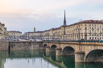 Turin street life, Italy, Torino skyline with the Mole Antonelliana and bridge on the Po River. People walking car traffic, smog and pollution.