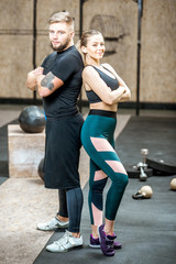 Portrait of a young athletic couple in black sports wear standing in the gym