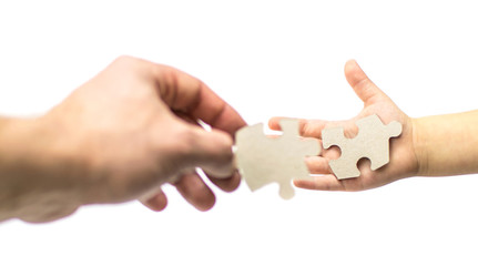 Hand of an adult and child with puzzles on a white background. Isolated. The concept of mutual understanding with the child.