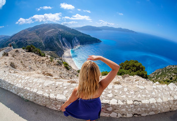 Beautiful young woman tourist looking at Myrtos Beach in Cephalonia Island Greece from above
