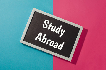 Study Abroad - text on chalkboard on blue and pink bright background.