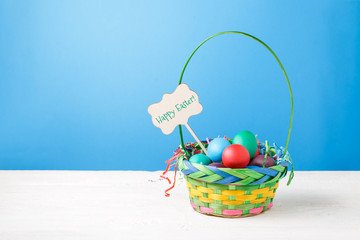 Picture of basket with colorful eggs with wish for happy Easter