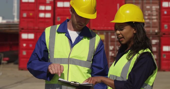 Dock workers discuss logistics at the harbor amidst shipping industry activity. Shot on RED Epic.