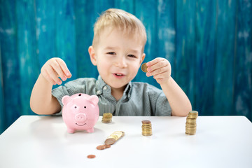 three years old child sitting st the table with money and a piggybank