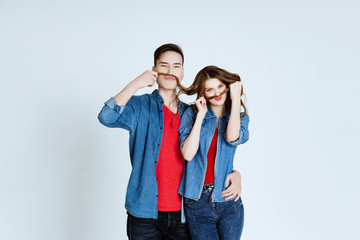 Portrait of happy young couple embracing on white background. The man and the woman play the fool and laugh