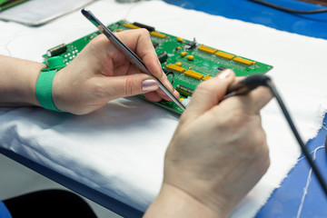 The process of assembling an electronic module. The worker's hands place electronic components on the printed circuit board.