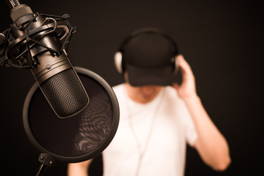 asian male singer listening backing track before singing a song in recording studio, focus on microphone