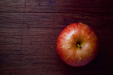 red apple with water drop on wooden table
