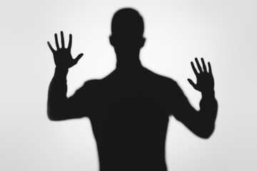 mysterious blurry shadow of person raising hands on grey