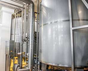 Large stainless steel barrels connected by pipes in the factory industry