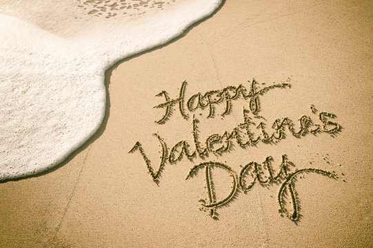 Happy Valentine's Day message handwritten on smooth sand beach