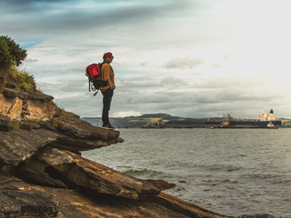 Obraz premium A female tourist, standing on the rocks and looking at the river.